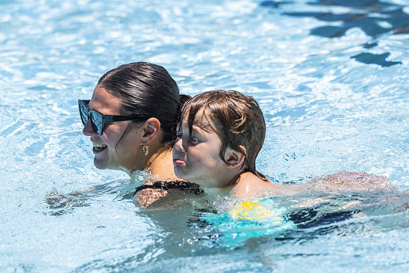 Louis, 4, hitches a ride with mom Kelle Bliss of Sterling Wednesday, June 5, 2024 during the season opener at the Polo pool.