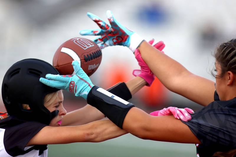 McHenry’s Madison Rupert, left, tussles with Huntley’s Natalia Turk on a pass intended for Turk in varsity flag football at Huntley High School in Huntley on Tuesday, Sept. 9, 2025.