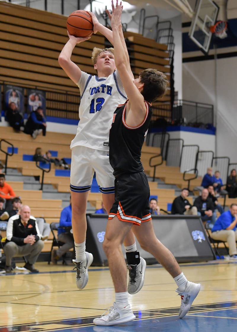 St. Charles North's Parker Reinke (12) takes a shot over Wheaton Warrenville South Nick Brooks (15) during a game on Friday, December 2, 2022.