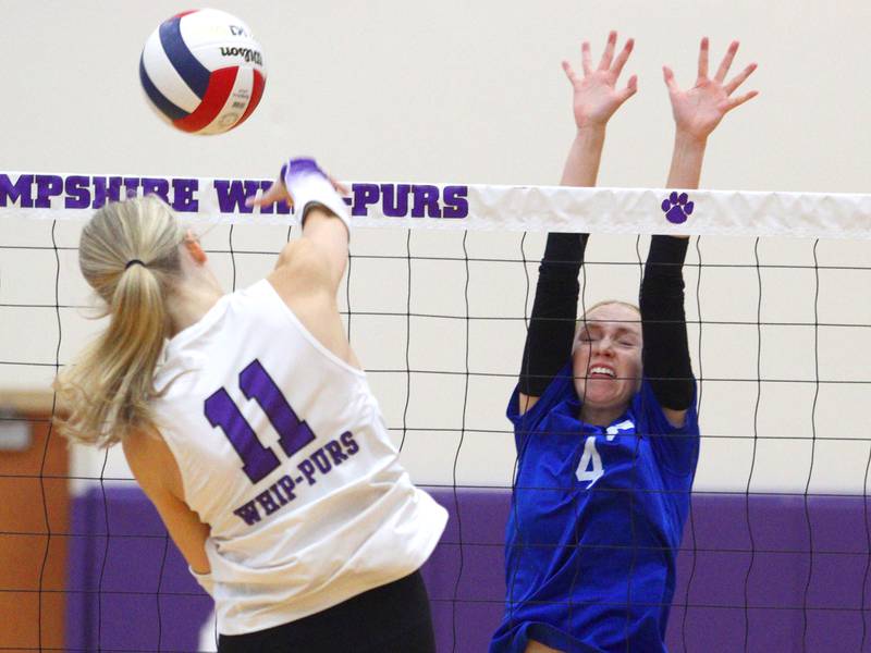 Hampshire’s Jorah Rutter, left, slams the ball as Woodstock’s Kendall O’Dea blocks in varsity volleyball tournament action on Saturday, Sept. 21, 2024, at Hampshire High School in Hampshire.