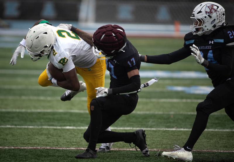 Providence Catholic's Xavier Coleman, left, carries the ball as Kankakee's Jayden Jones, center, and Isaiah Robinson, right, attempt to tackle during a Class 5A playoff game on Saturday, November 8, 2025.