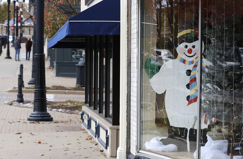 A snowman appears to wave at shoppers from the Backdrop’s store front window Tuesday, Nov. 12, 2024, in Woodstock.