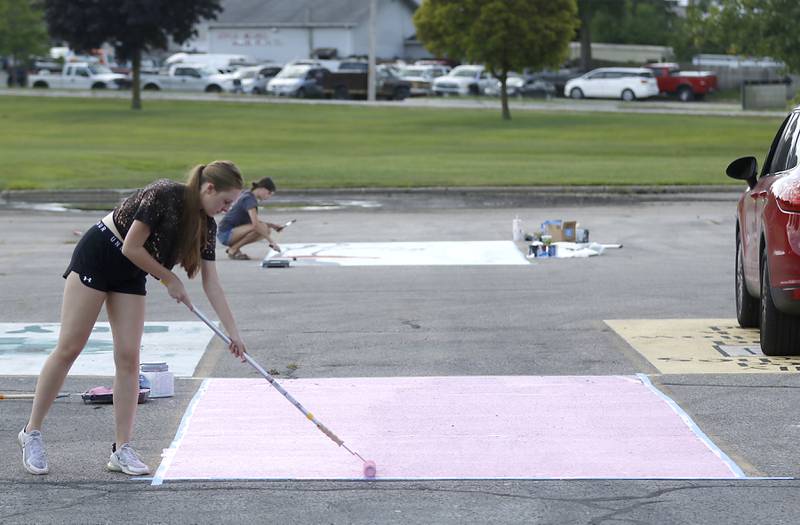 Marian Central Catholic High School senior Katie Maynor paints the pink background as she starts painting her parking spot on Tuesday, Aug. 13, 2024, at the school in Woodstock.