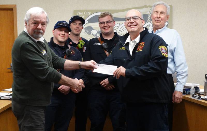 Oregon Mayor Ken Williams, left, presents a check for $17,282.22 to the Oregon Fire Protection District for the purchase of a Stryker LUCAS 3 chest compression system. The funds are from the city's American Rescue Plan Act allocations.
