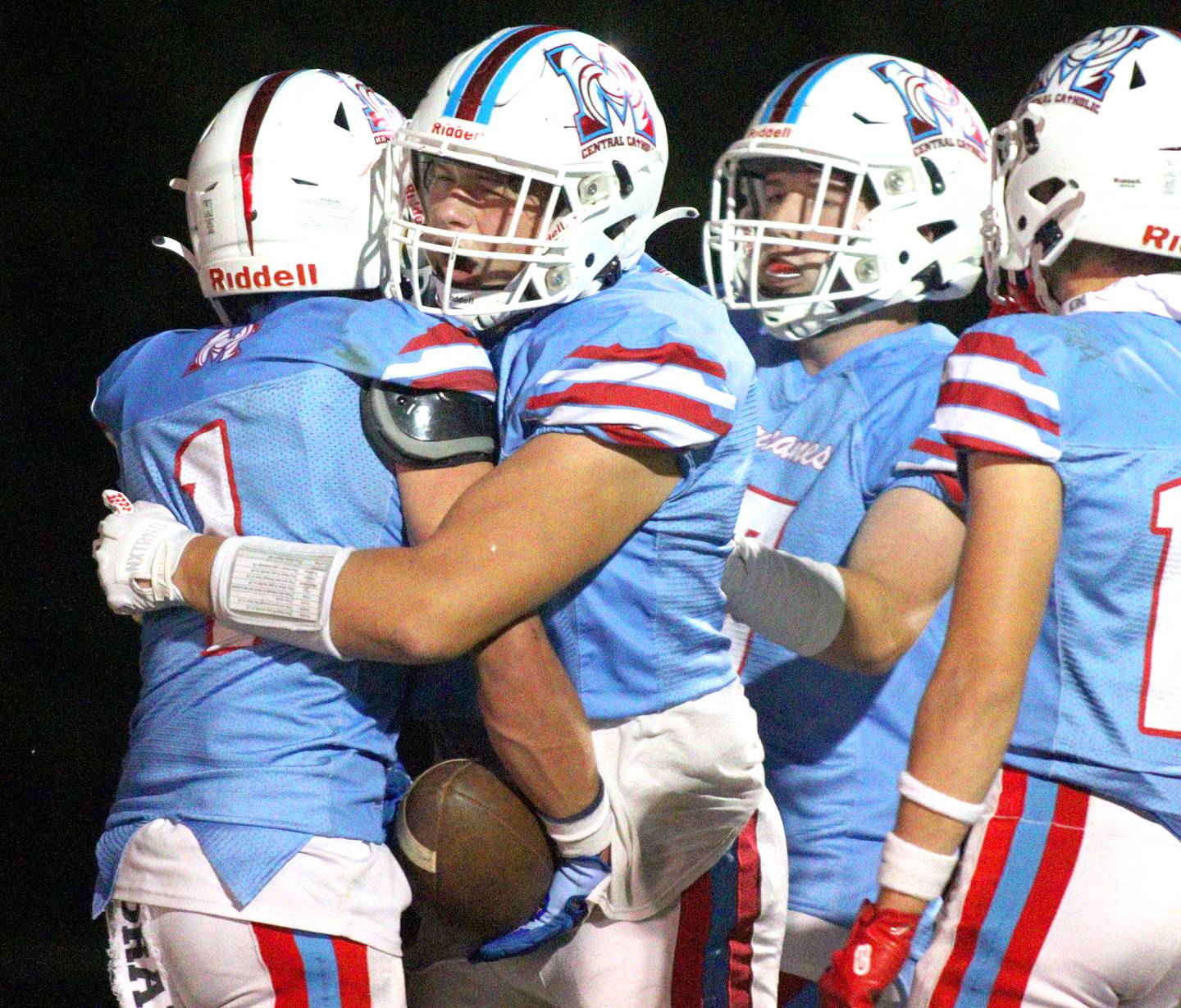 Marian Central’s Eddie Kowalczyk, left, is greeted after a touchdown run by teammates Justin Jakubowicz, center, and Eddie Gilmore, center right, in varsity football against Aurora Christian at George Harding Field on the campus of Marian Central High School in Woodstock on Friday, Oct. 11, 2024.