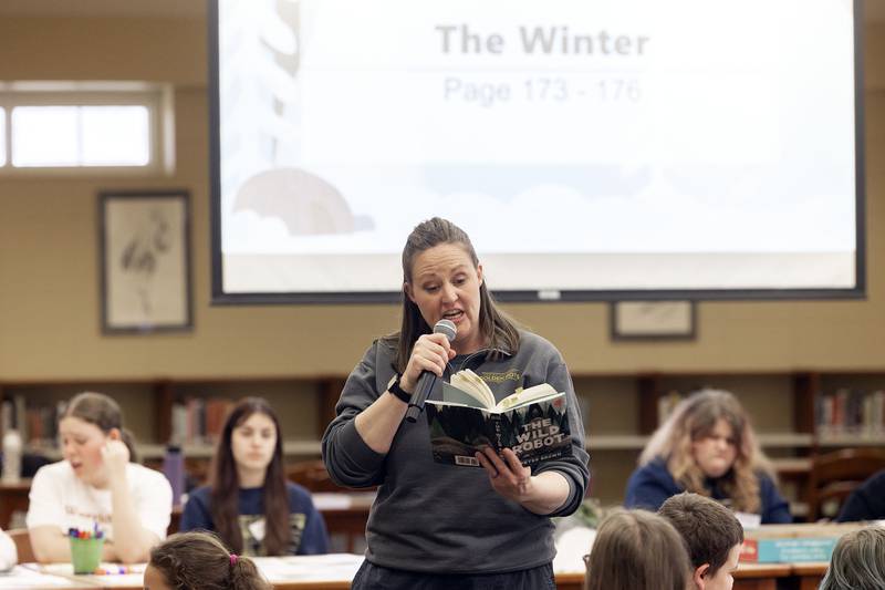 Sterling High School librarian Heather Johnson reads aloud to a group of Lincoln School fourth graders Thursday, March 23, 2023 from the book “The Wild Robot.” Students then participated in a series of STEM challenges related to the book, such as completing a puzzle or building a shelter against a winter storm.