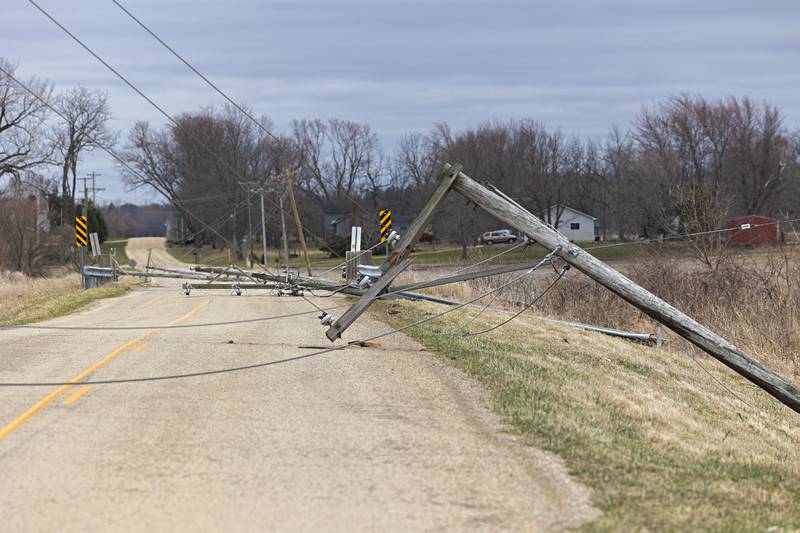 Downed power poles block a lane of traffic outside of Amboy Saturday, April 1, 2023.
