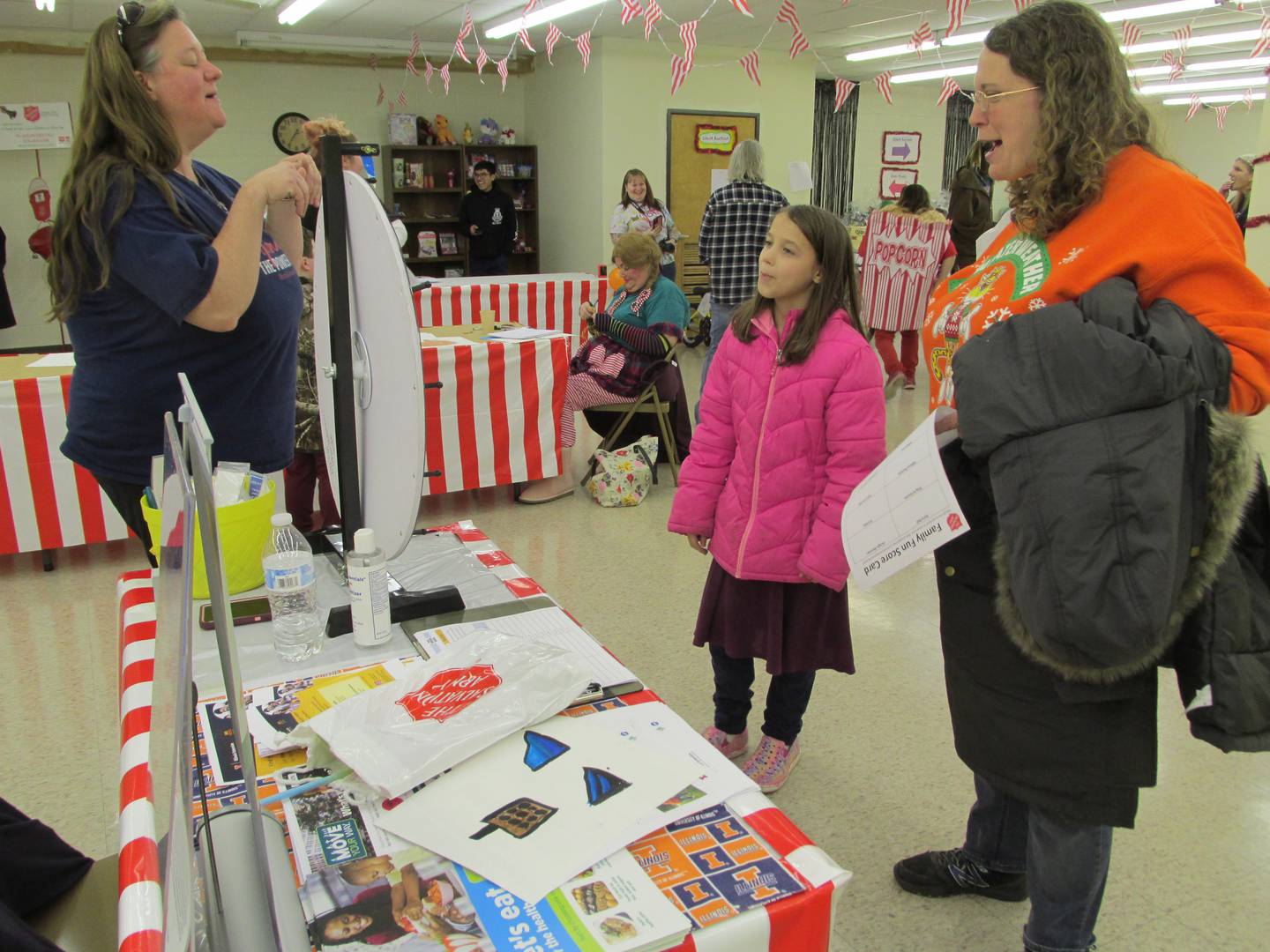 Laura Masters spins the wheel and has to hop like a bunny Saturday, Nov. 12, 2022, during the Family Fun Fair at the Salvation Army in Ottawa. Shasta Hladovcak shows gives her a demonstration as Laura's aunt Carolyn Claahsen looks on.