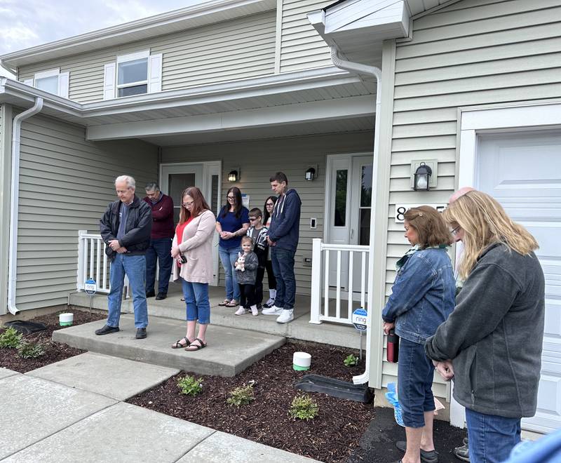 Habitat for Humanity McHenry staff prays with new homeowners of two duplex homes during a home dedication ceremony in Wonder Lake on Saturday, May 13.