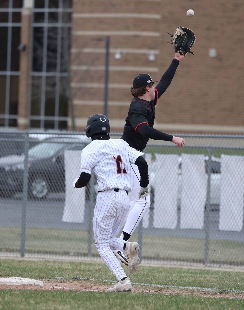 DeKalb's Benjamin Nunez is safe at first as the throw goes over the head of Harlem's Jackson Heidemann during their game Tuesday, April 1, 2025, at DeKalb High School.