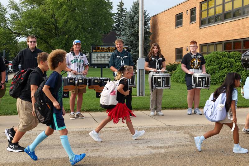 Herscher High School drumline members smile as they welcome Herscher Intermediate School students arriving for the first day of school on Tuesday, Aug. 19, 2025.