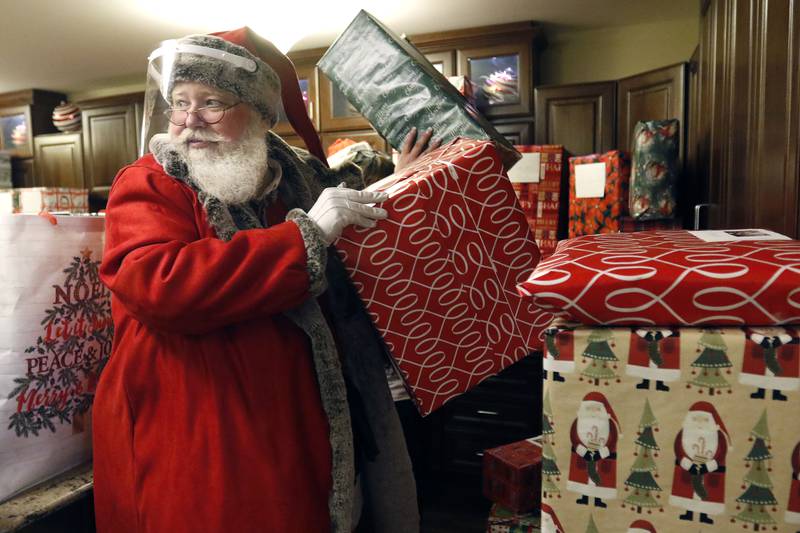 Santa Claus helps deliver presents during an adopt-a-grandparent gift event at Gable Point Senior Housing on Wednesday, Dec. 22, 2021, in Crystal Lake.