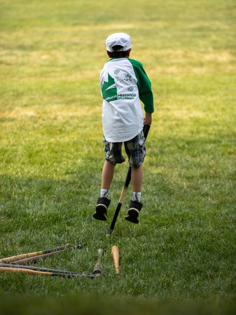 Batboy Karsten Oberg jumps on a bat during the Elmhurst Heritage Foundation's Vintage Baseball Game at Elmhurst University Mall on Sunday, June 4, 2023.