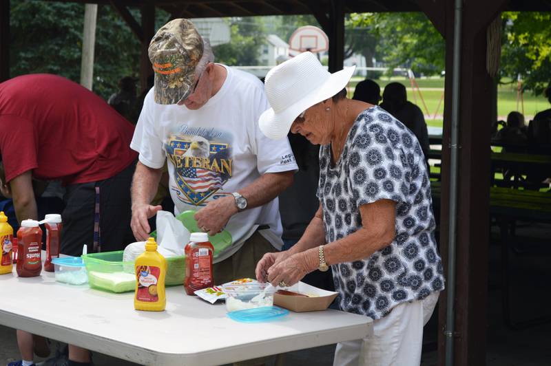 Judy Groeling, right, of Shannon, puts condiments on her hotdog on Saturday, Aug. 5, 2023, during Forreston Sauerkraut Days' sauerkraut lunch.