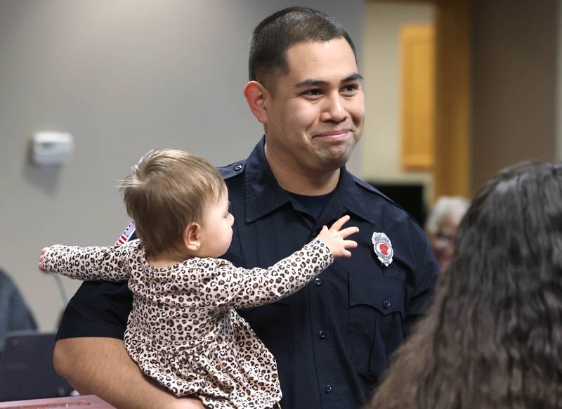 New Sycamore firefighter Carlos Aburto smiles while holding daughter Sophia Aburto after having his badge pinned on by girlfriend Stephanie Starks Monday, April 1, 2024, during the Sycamore City Council meeting in the chambers at Sycamore Center.