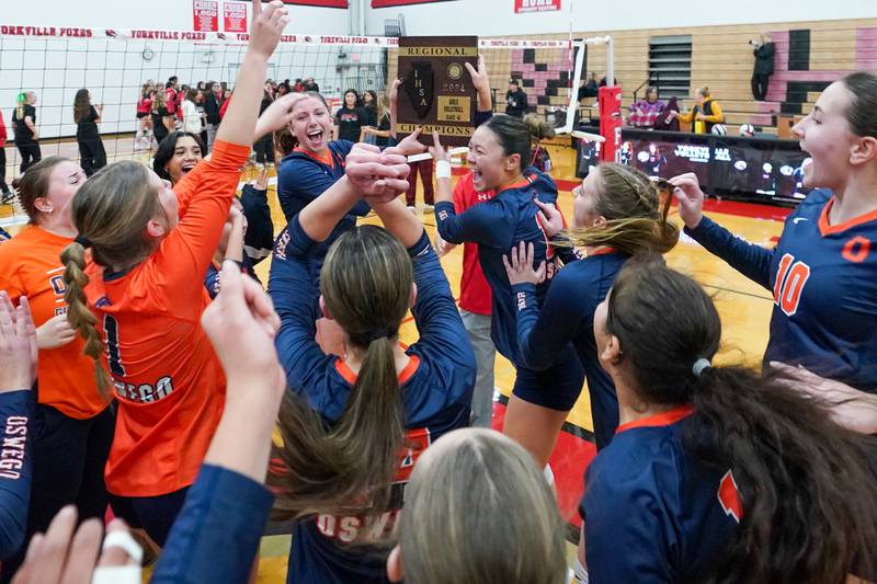 Oswego’s Kelsey Foster (right) and Ava Flanigan (left) hold up the regional championship plaque after defeating Yorkville in two sets to win the Class 4A Yorkville Regional final at Yorkville High School.