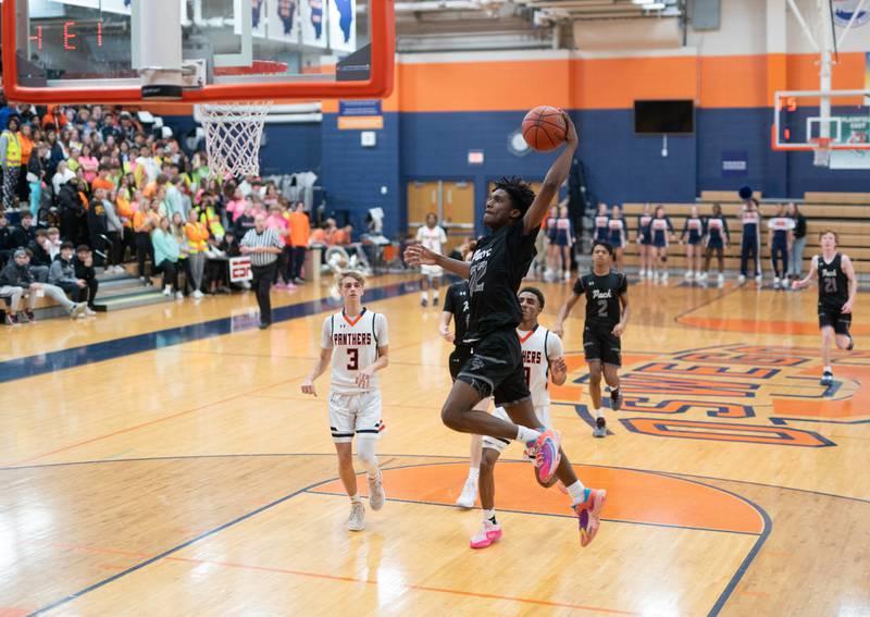 Oswego East's Jehvion Starwood (22) goes up for a slam dunk against Oswego during a basketball game at Oswego High School on Tuesday, Dec 12, 2023.