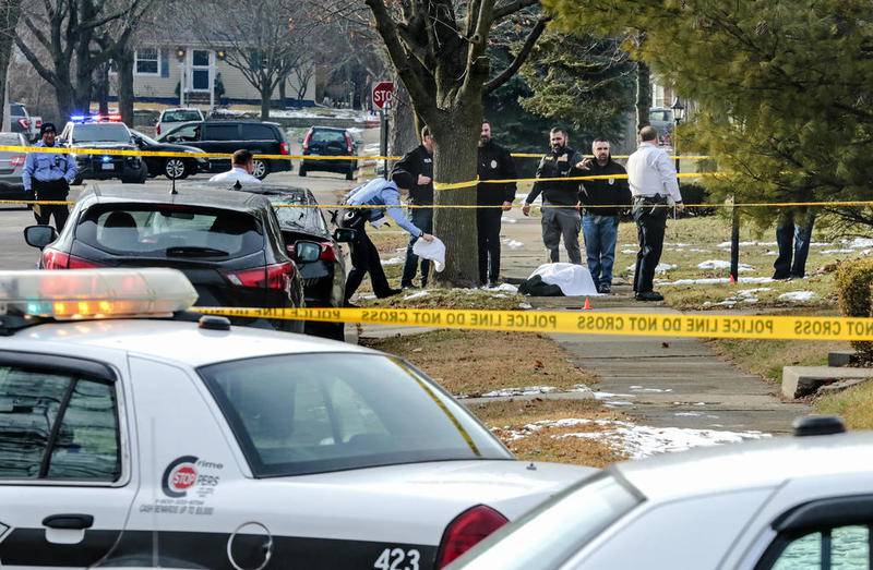 Police and investigators secure the scene of a shooting Friday as a shooting victim lays on the sidewalk along Sherwood Place in Joliet. One man was killed and a woman was taken to an area hospital with an injury.