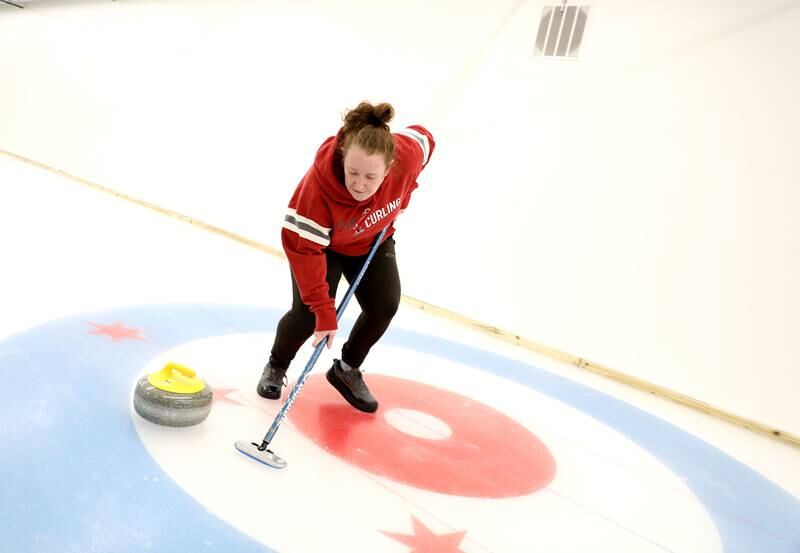 Sweeper Siobhan Cogswell sweeps ahead of the stone during a drop-in game of Curling at the Windy City Curling Club in Villa Park.