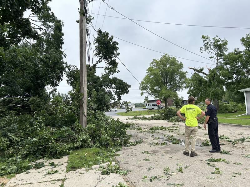 Byron Police Chief Jeremy Boehle speaks with a city worker as they survey storm damage on Colfax and W. Second streets in Byron, on Tuesday, July 16, 2024. A strong storm ripped through the town Monday night felling trees, damaging homes, and knocking out electrical service.