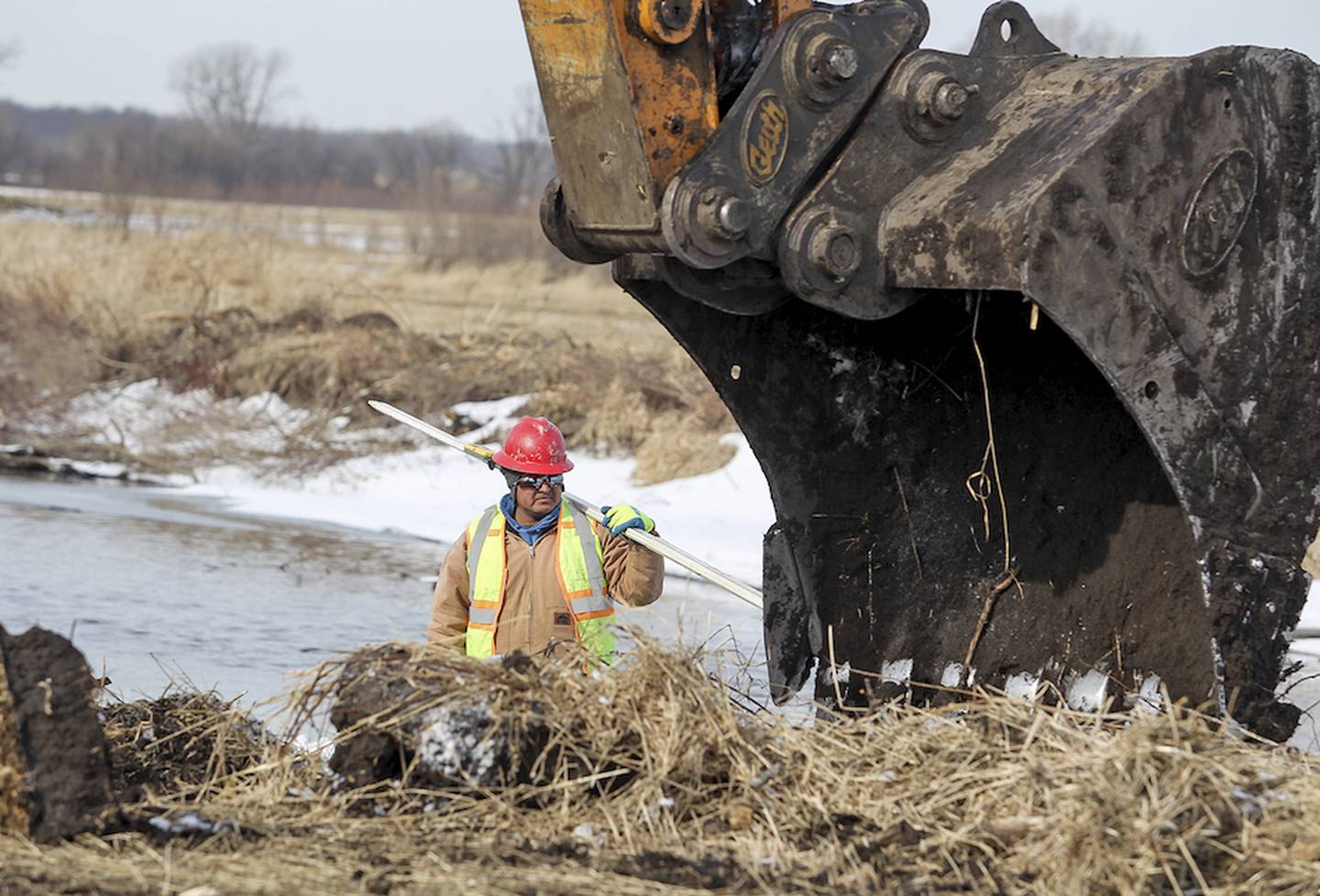 Earth Werks contractor Omar Alaniz checks the elevation while contractors work on grading the streambank back on the Nippersink Creek at Glacial Park in Ringwood Wednesday, January 28, 2015.  A joint five-year project between the McHenry County Conservation District and the U.S. Army Corps of Engineers to restore 3.5 miles of Nippersink Creek and 507 acres of sedge meadow, wet prairie and wet mesic oak savanna is currently in process to potentially alleviate some flooding and may also mean better water quality, a better wildlife and fish habitat and easier access to the creek for those fishing, kayak and canoe users.