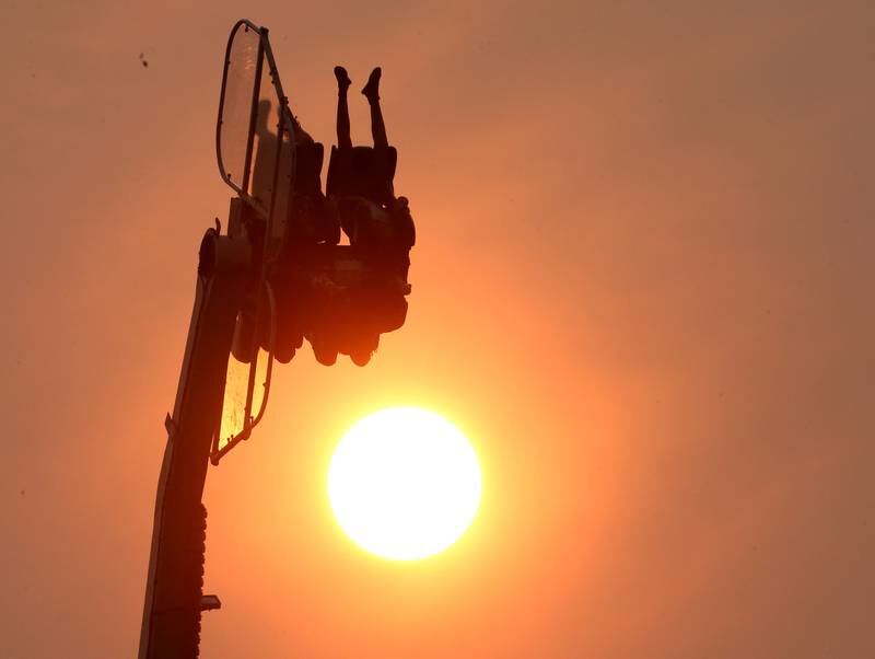 People hang upside down as the sun sets over the Oglesby Summer Fun Fest on Thursday, June 15, 2023 in Oglesby. Canadian wild fires created hazy sky's over the Illinois Valley. The Oglesby Fun Fest runs through Sunday.