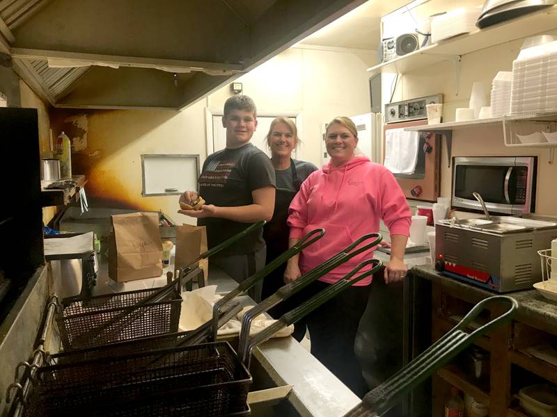 Caleb Reymer, Jill Nyenhuis, and Amanda Reymer (L-R) are pictured by the grill during their final day of business at the Pink Pony Drive In on Sunday, Jan. 2.