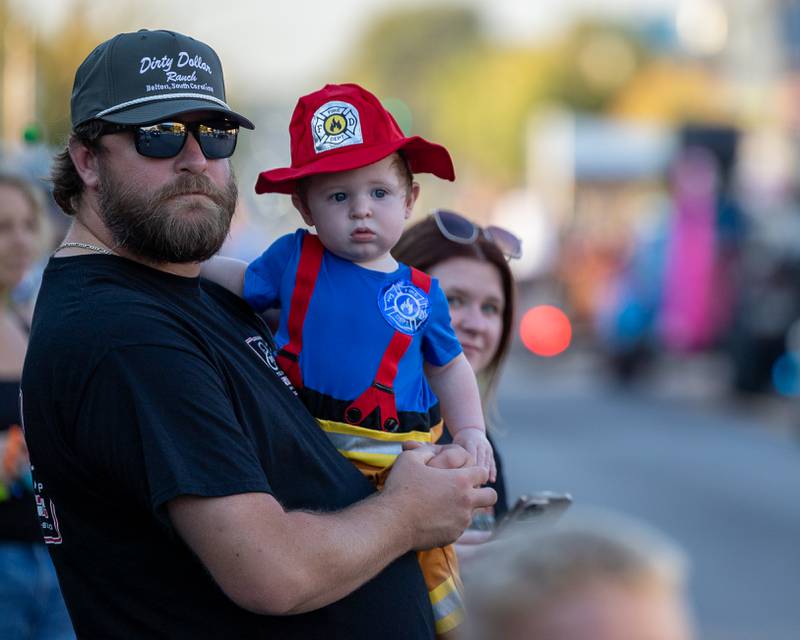 (from left) Brandon Chapman holds son Brayden as they watch the annual Princeton Halloween Parade on Saturday, Oct. 4, 2025 on Main Street in Princeton.