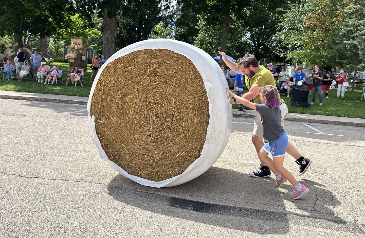 Jake and Emmie Nicholson of Mt. Morris roll a large round straw bale down Wesley Avenue in Mt. Morris during the Straw Bale Race at Strawfest on Saturday, Aug. 23, 2025. The team with the fastest time won the event. The father/daughter team posted a best time of 11.5 seconds.
