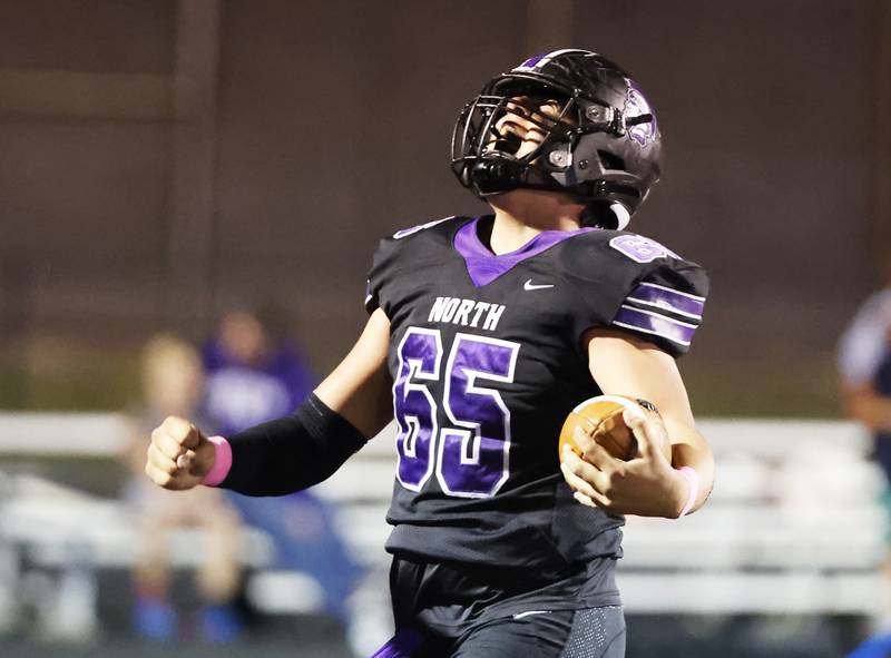 Downers Grove North's Aiden Solecki (65) celebrates his interception and touchdown during the varsity football game between Downers Grove North and Lyons Township on Friday, Oct. 11, 2024 in Downers Grove.