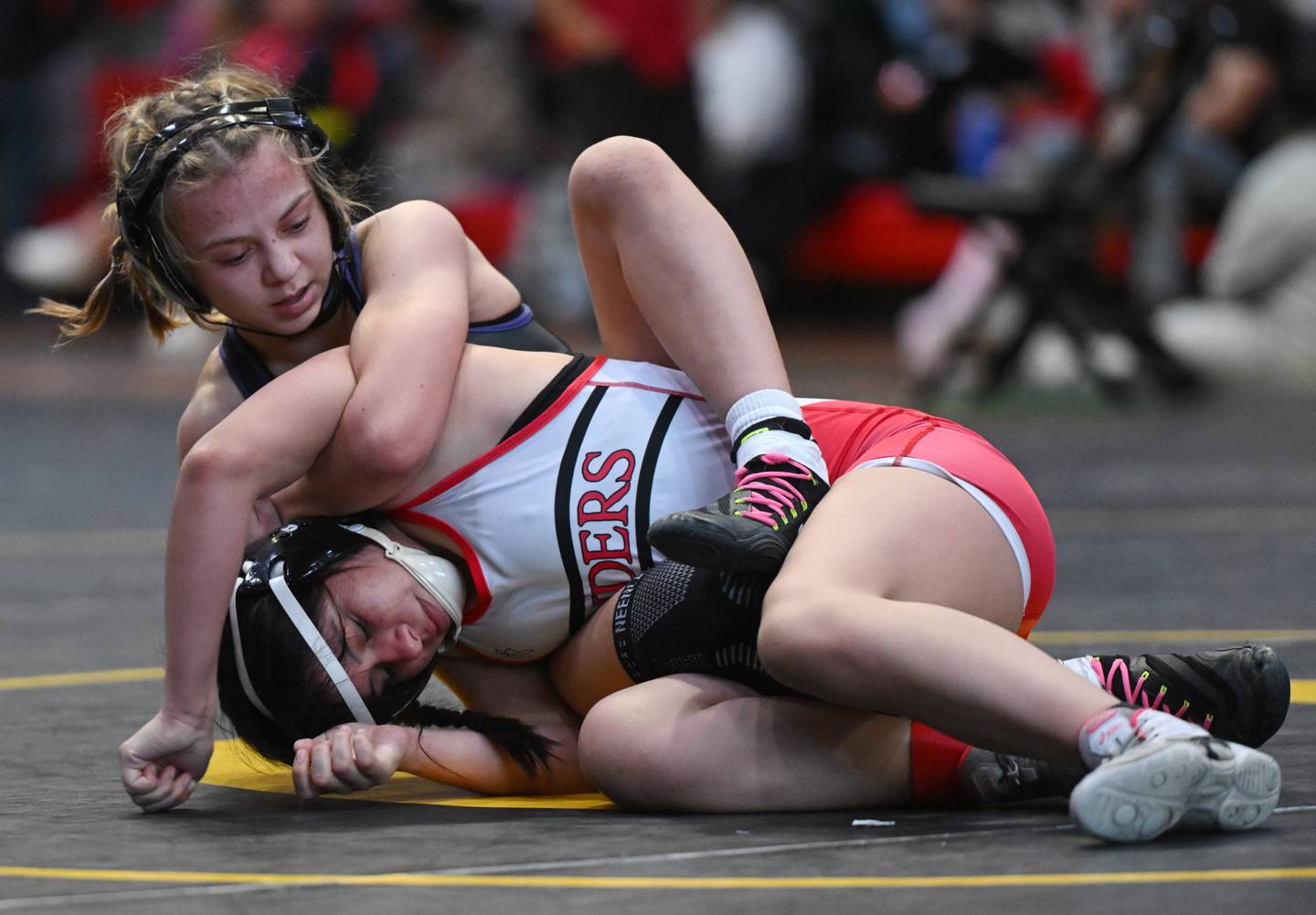 Hampshire’s Amelia Nidelea-Polanin, top, wrestles Bolingbrook’s Alejandra Flores in the 115-pound final match during the Schaumburg girls wrestling sectional Saturday.