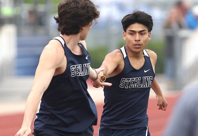 Sterling's John Cid hands the baton off to Jordan Britt for the final leg of the 4x800 meter relay Wednesday, May 18, 2022, at the Class 2A boys track sectional at Rochelle High School.