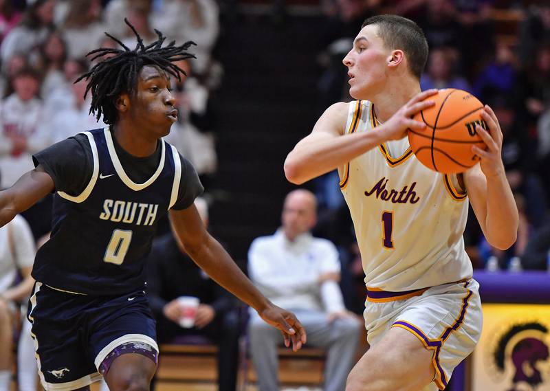 Downers Grove North’s Colin Doyle (1) starts to pass as Downers Grove South’s Antonio Evans Jr. defends during a game on December 20, 2025 at Downers Grove North High School in Downers Grove.