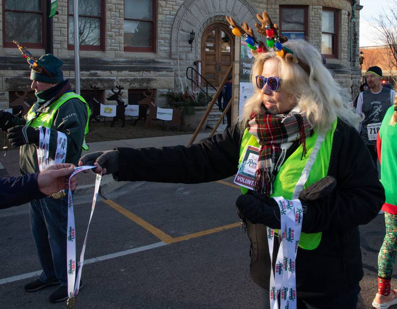 Lions Club volunteer Cheryl Diener hands out medals at the end of the 13th annual Lions Charities Reindeer Run 5K Wheaton on Saturday, Dec. 7, 2024.