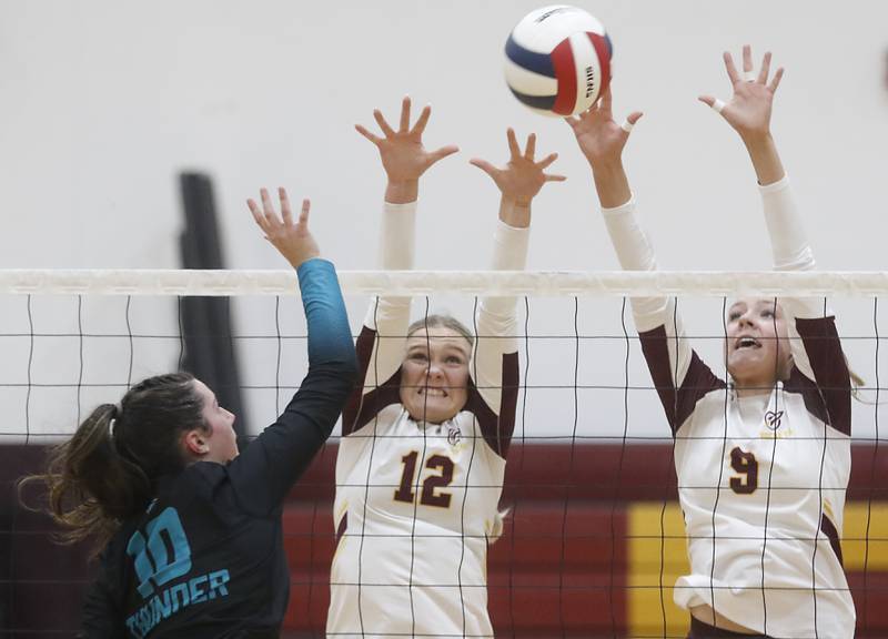 Woodstock North's Ava Kardaras (left) tries to hit the ball past the block of Richmond-Burton's Zoe Freund and Reagan Wisniewski during a Kishwaukee River Conference volleyball match on Wednesday, Oct. 15, 2025, at the Richmond-Burton High School in Richmond.