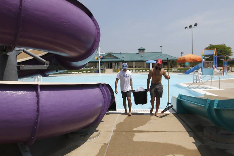 Lifeguards Jared Kniola and Jacob Brucker clean a slide Wednesday, May 24, 2023, at the Woodstock Water Works Aquatics Center in Woodstock as the pool gets ready to open on Saturday.