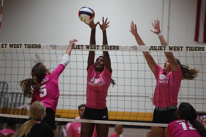Joliet West’s Iyonna Pike, center, goes for the block against Joliet Central in the JTHS Pink Heals match. Tuesday, Oct. 4, 2022, in Joliet.