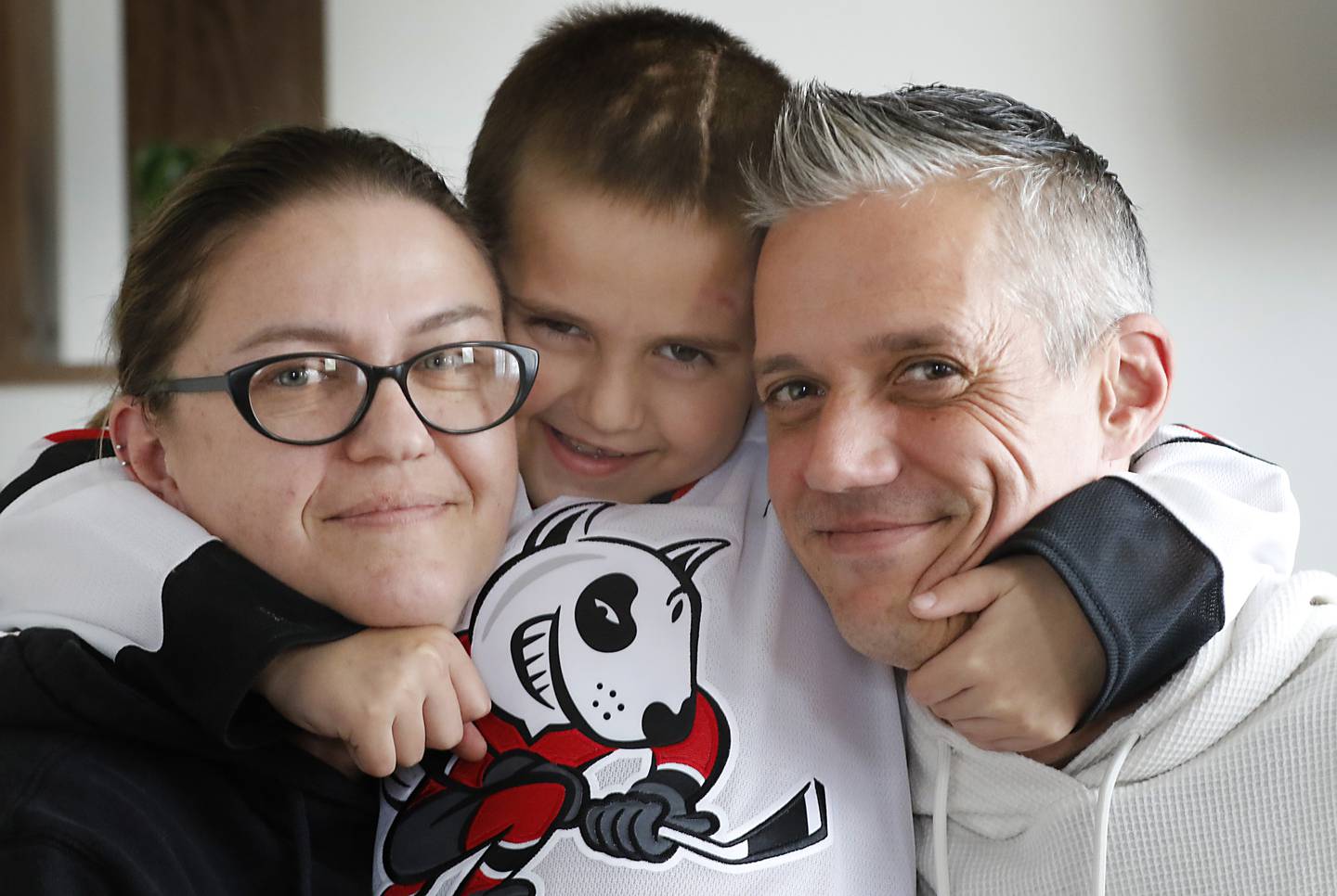 Alex Moscrip, 7, son of Brad and Aleksandra, with his parents on Wednesday. Nov 13, 2024 at his home in McHenry Township. Hewas hit by a car in July and left with traumatic brain injury and is now recovering at home.