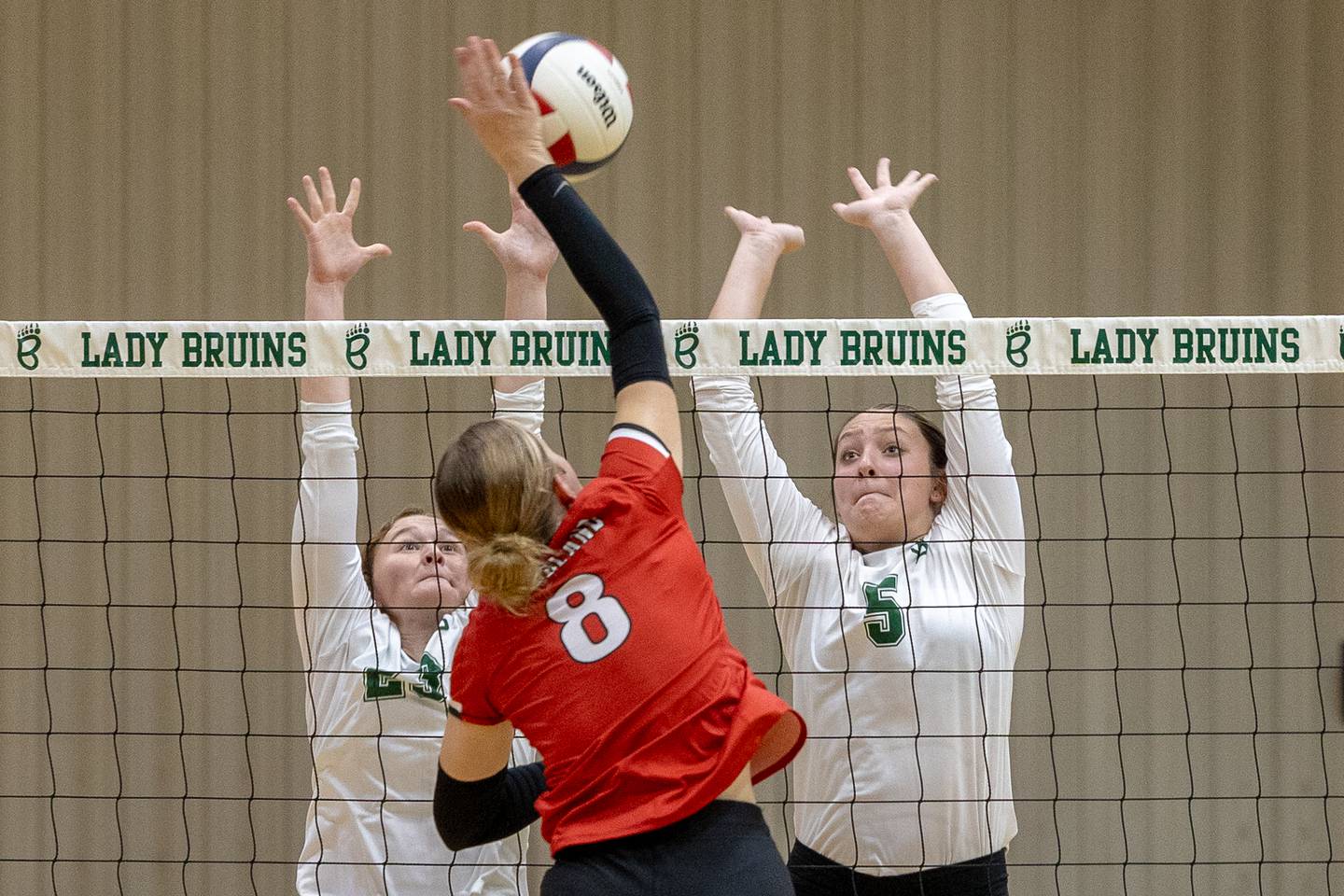 Grace Longmire (8) of Woodland hits ball over net as (from left) Lili McClain (23) of St. Bede and teammate Jillian Pinter (5) jump to defend on Thursday, Sept. 11, 2025 at Abbot Vincent Gymnasium in Peru.