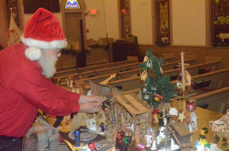 Santa adjusts lighting on one of 60 nativity sets displayed Friday evening, Dec. 5, 2025 at Church of the Good Shepherd United Methodist of Oswego during the annual Oswego Christmas Walk.