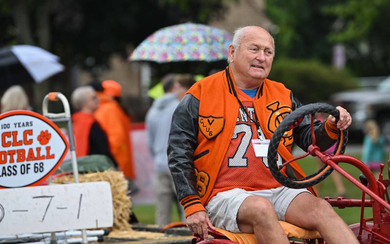 A member of Crystal Lake Central High School's 1968 football team drives a tractor in the 100th year anniversary homecoming day parade that featured alumni from various graduating classes on a rainy Saturday, Sep. 16, 2023 in Crystal Lake. The parade began at the high school and made its way through downtown Crystal Lake.