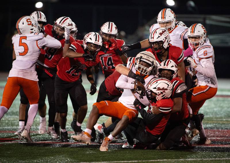 A pack of Bradley-Bourbonnais players bring down Shepard's Aarien Lee, center, in a Class 6A playoff game on Friday, October 31, 2025.