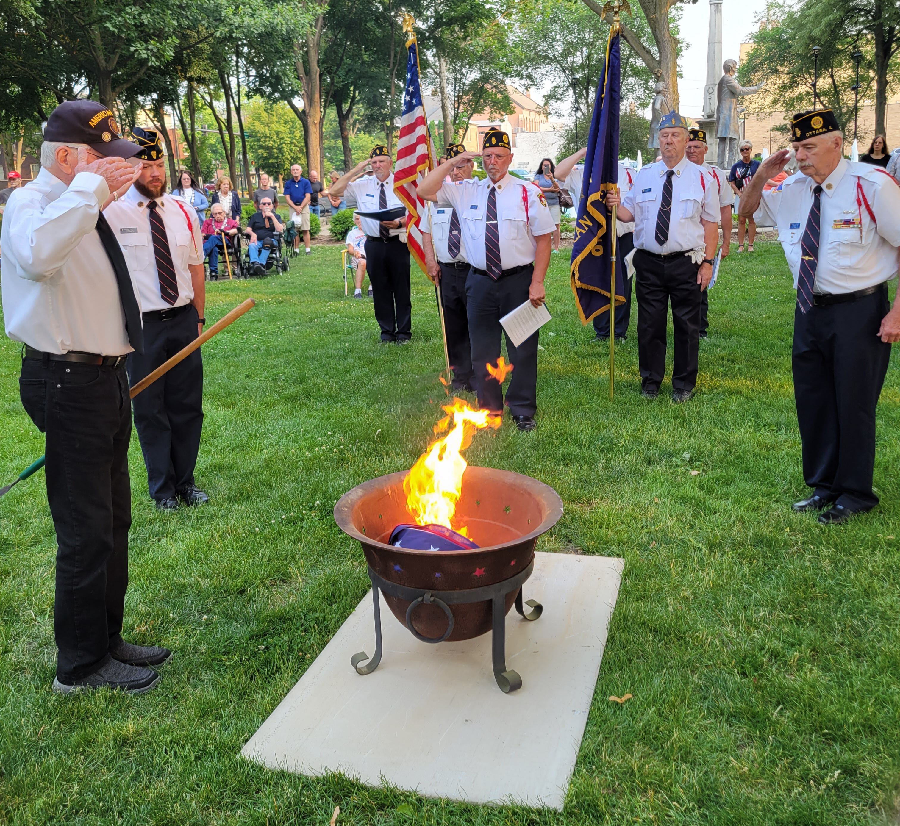 Members of the Ottawa American Legion Post 33 salute a burning American flag, the culmination of a demonstration of how to properly dispose of a retired flag Wednesday, June 14, 2023, during Flag Day ceremonies at Washington Square.