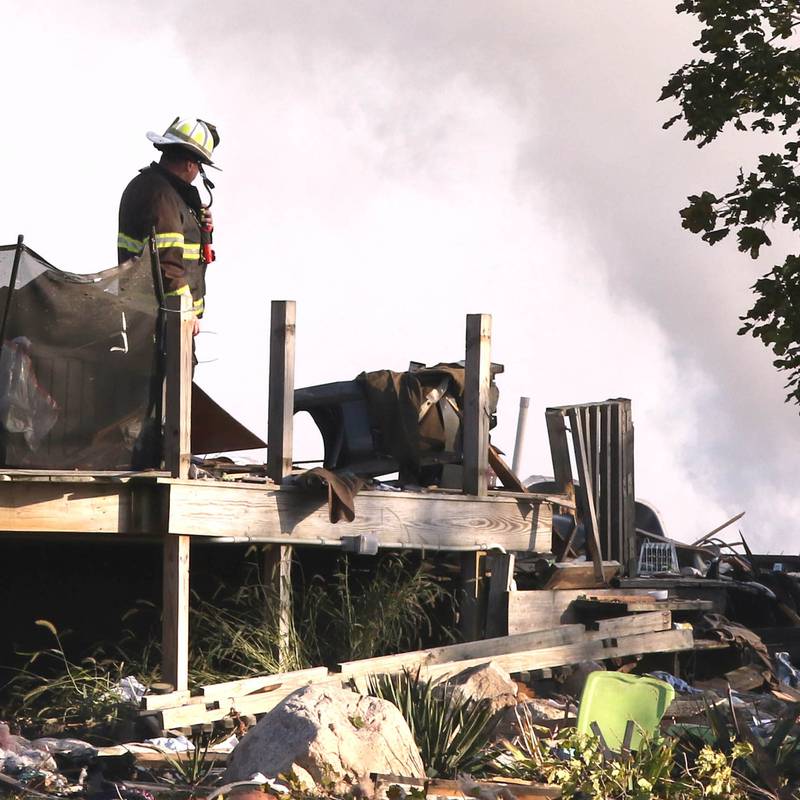 A firefighter overlooks the smoldering rubble that was a house Tuesday, Oct. 17, 2023, after an explosion at the residence on Goble Road in Earlville. Several fire departments responded to the incident at the single-family home that left one person hospitalized.