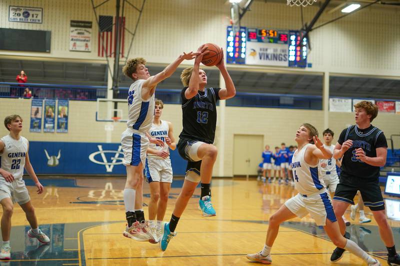 St. Charles North's Parker Reinke (12) drives to the hoop against Geneva’s Hudson Kirby (25) during a basketball game at Geneva High School on Wednesday, Feb 14, 2024.