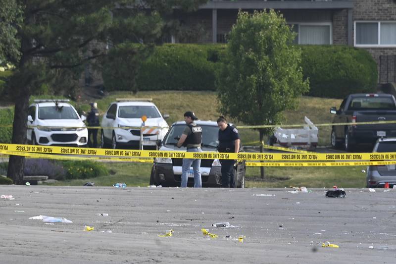 Investigators look over the scene of an overnight mass shooting at a strip mall in Willowbrook, Ill., Sunday, June 18.