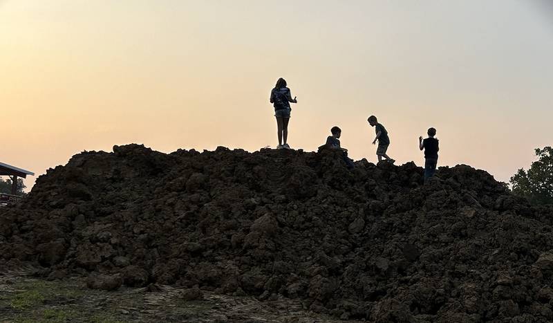 Kids play on top of a mound of dirt in the grandstand area at the Ogle County Fair before the start of the demolition derby on Saturday, Aug. 2, 2025.