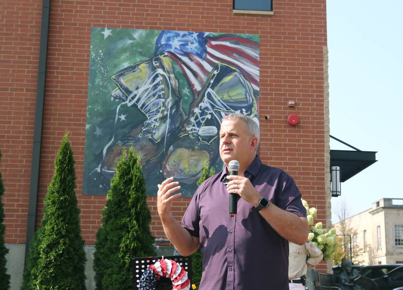 DeKalb Mayor Cohen Barnes speaks Thursday, Aug. 22, 2024, during the DeKalb Veterans Memorial Mural dedication. The mural, which is  is a re-creation of a painting by Mary Gallagher Stout titled “What These  Boots Have Seen,” is on the rear wall of the Plaza DeKalb building overlooking Van Buer Plaza.