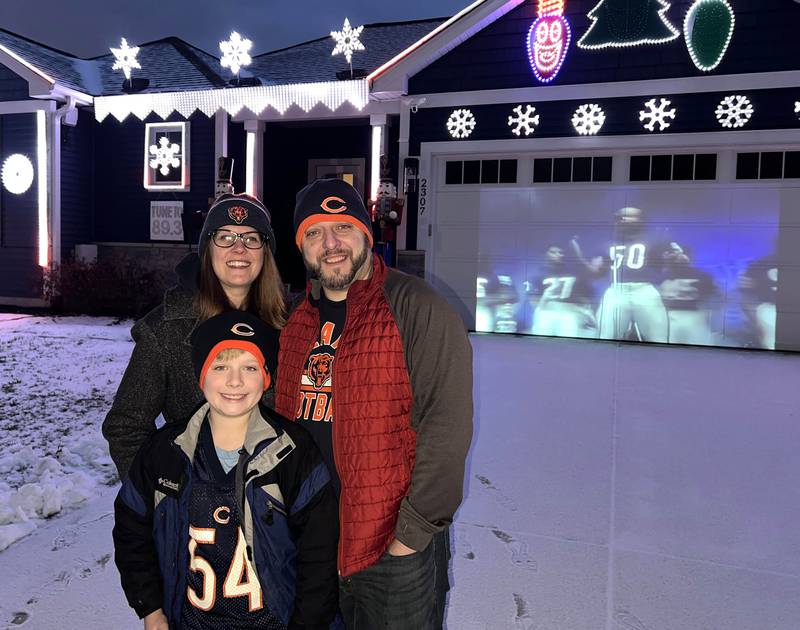 Tim Caravia, his wife Jen and son Emmett, 9, in front of their home as it plays a Chicago Bears light show Friday, Jan. 16, 2025, on Dustin Drive in Sycamore. The show will run from 5:30 to 9:00 p.m. most days until the Bears season ends.
