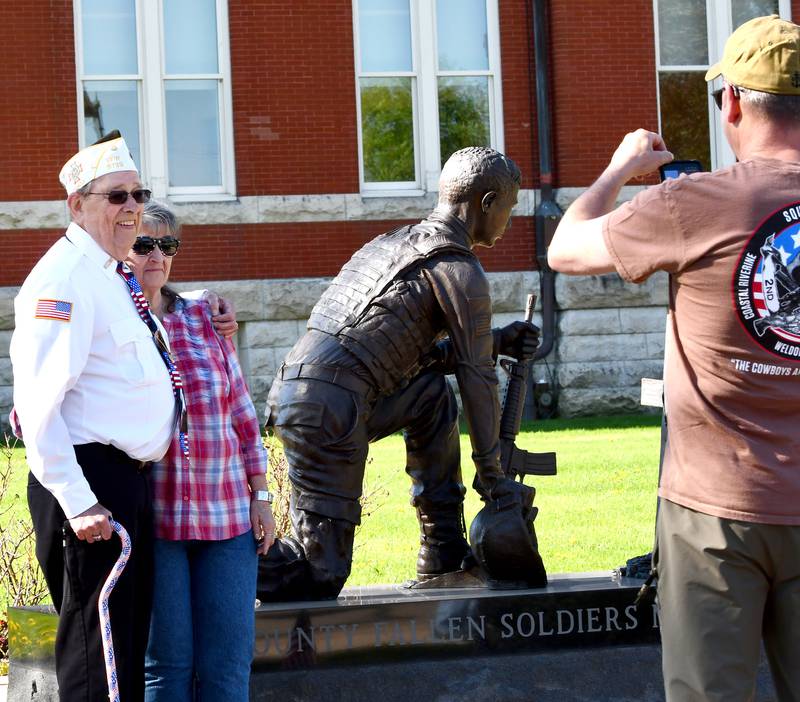 Oregon veteran Lee Ossmann and his wife, Sue, pose for a photo by the veteran's memorial on the north side of the Ogle County Courthouse Square on Thursday, April 23, 2026. Ossmann's Hometown Hero banner was the first installed on a city street pole in downtown Oregon during the morning event.